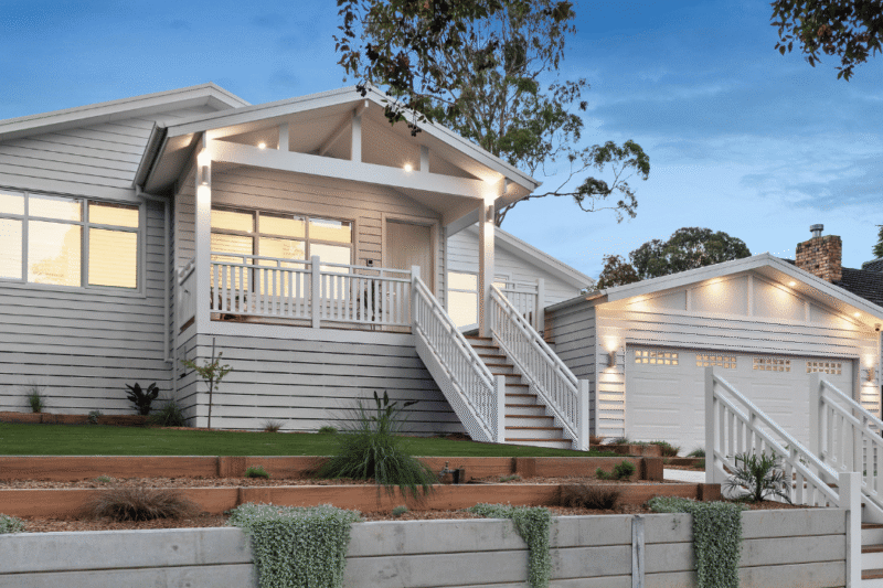 Custom home on a sloped block built by expert Ringwood builders, showcasing elevated design with tiered landscaping and split-level access.